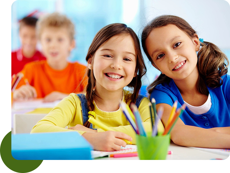 Two children sitting at a table with pencils.