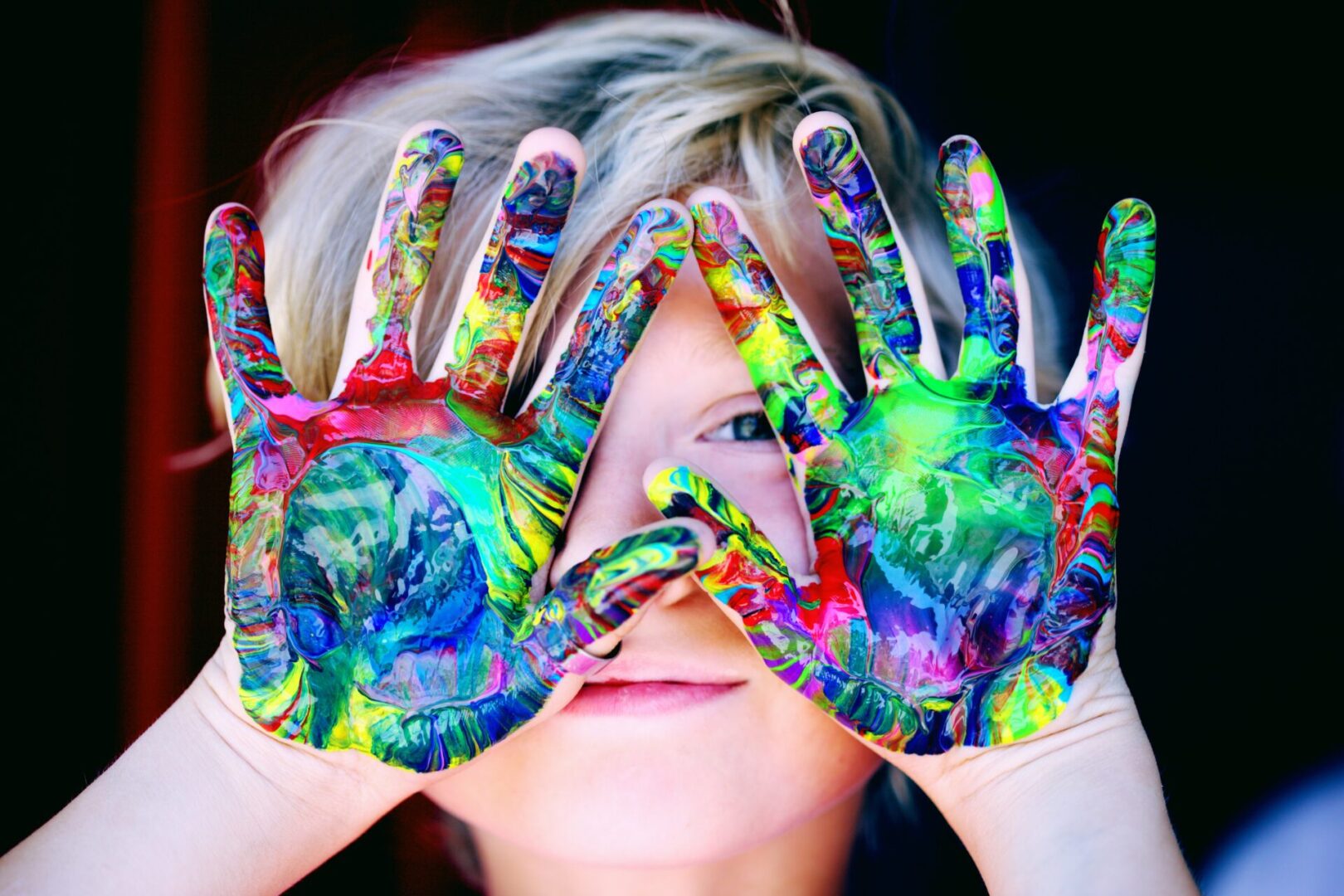 A woman with paint on her hands covering her eyes.