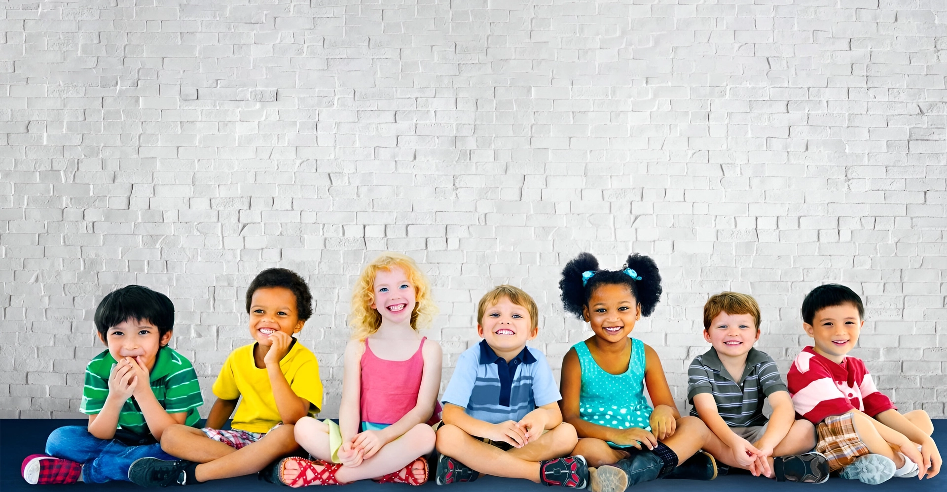 Children sitting against brick wall